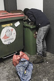 Um freegan realizando o dumpster diving, mergulho na lixeira ou garimpo urbano.
